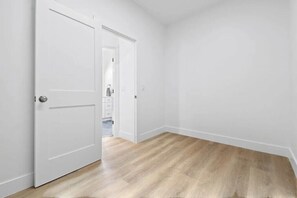 Ein Zimmer mit Holzboden, weißen Wänden und geschlossener Tür.