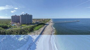 Un hotel costero con varias edificaciones, una playa y un muelle que se adentra en el mar.
