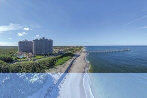Ein Hotel an der Küste mit mehreren Gebäuden, einem Strand und einem Steg, der ins Meer führt.
