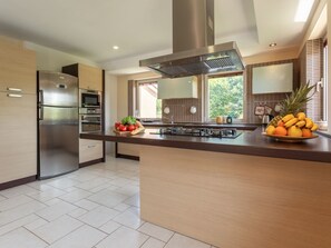 A modern kitchen with stainless steel appliances, a central island with fruit, and a large window providing natural light. - in Medulin mit Privatem Pool by Interhome (Medulin)