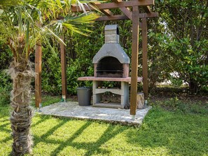 A stone-built outdoor pizza oven under a wooden pergola, surrounded by lush greenery. - in Medulin mit Privatem Pool by Interhome (Medulin)