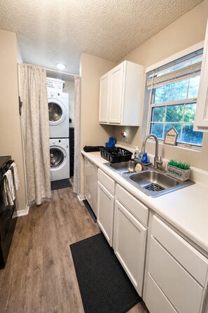 A compact laundry room with a washing machine, dryer, and a sink with a window above it. - 3BR Near Downtown, Zoo Atlanta, & BeltLine (Atlanta)