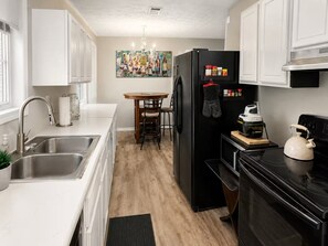A compact kitchen with a sink, a dining table, a refrigerator, and a stove. - 3BR Near Downtown, Zoo Atlanta, & BeltLine (Atlanta)