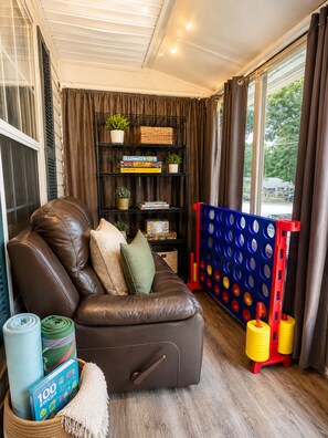 A cozy living room with a leather sofa, a bookshelf, and a window with curtains. - 3BR Near Downtown, Zoo Atlanta, & BeltLine (Atlanta)