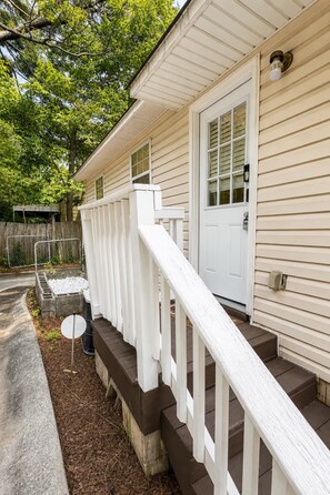 A house with a white front door, a small porch with a white railing, and a concrete foundation. - 3BR Near Downtown, Zoo Atlanta, & BeltLine (Atlanta)