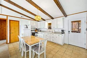 Een keuken met witte kasten, een houten eettafel en een hanglamp.