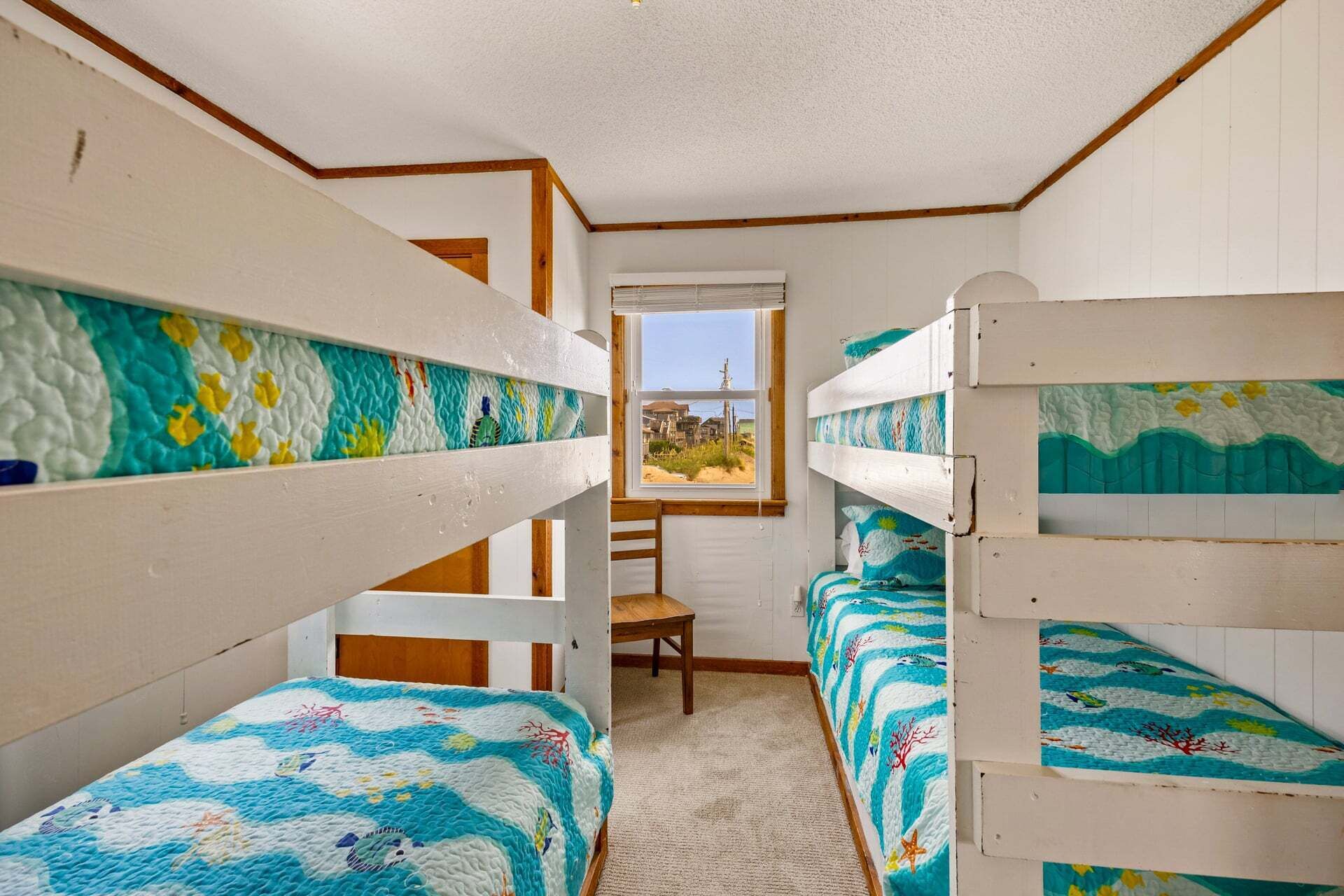 A room with bunk beds, a window with a view, and a chair.