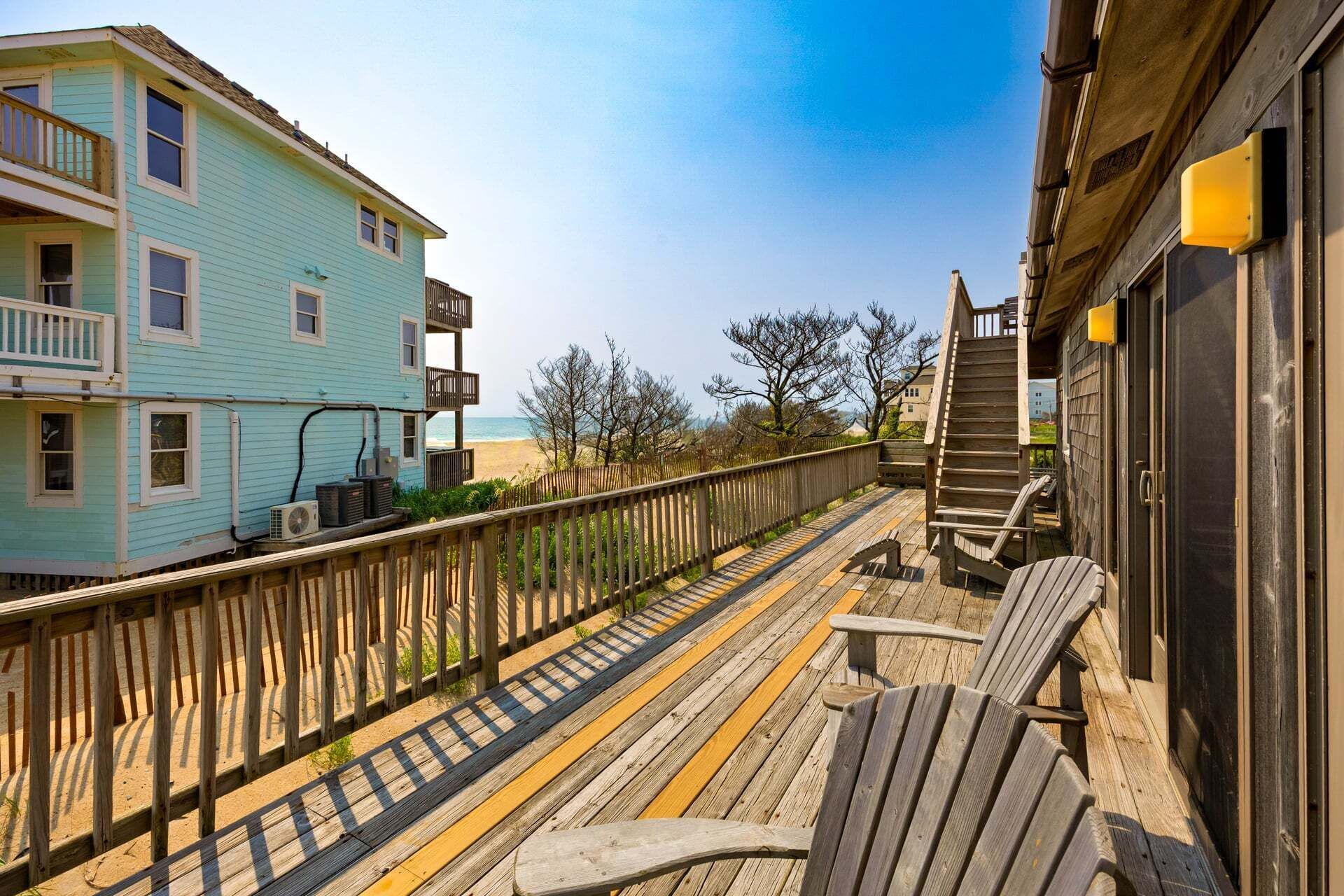 Une terrasse en bois avec une chaise, une clôture en bois et un bâtiment doté d’un balcon.