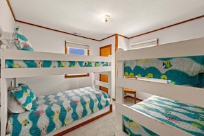 A bunk bed room with a nautical theme, including a bed with a quilted ocean design and a headboard with a fish illustration. - Saltwater Sunrise: Ocean Views & Beach Access (Rodanthe)