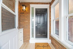 A front door with a black door, a white door frame, and a brick wall.
