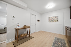 A hallway with a water dispenser, a woven basket, a door, and a wall-mounted artwork.