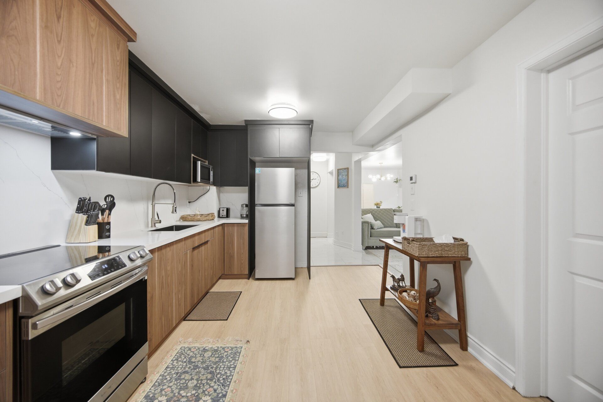 A modern kitchen with dark cabinetry, a stainless steel refrigerator, and a built-in oven.