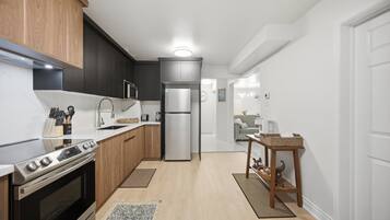 A modern kitchen with dark cabinetry, a stainless steel refrigerator, and a built-in oven.