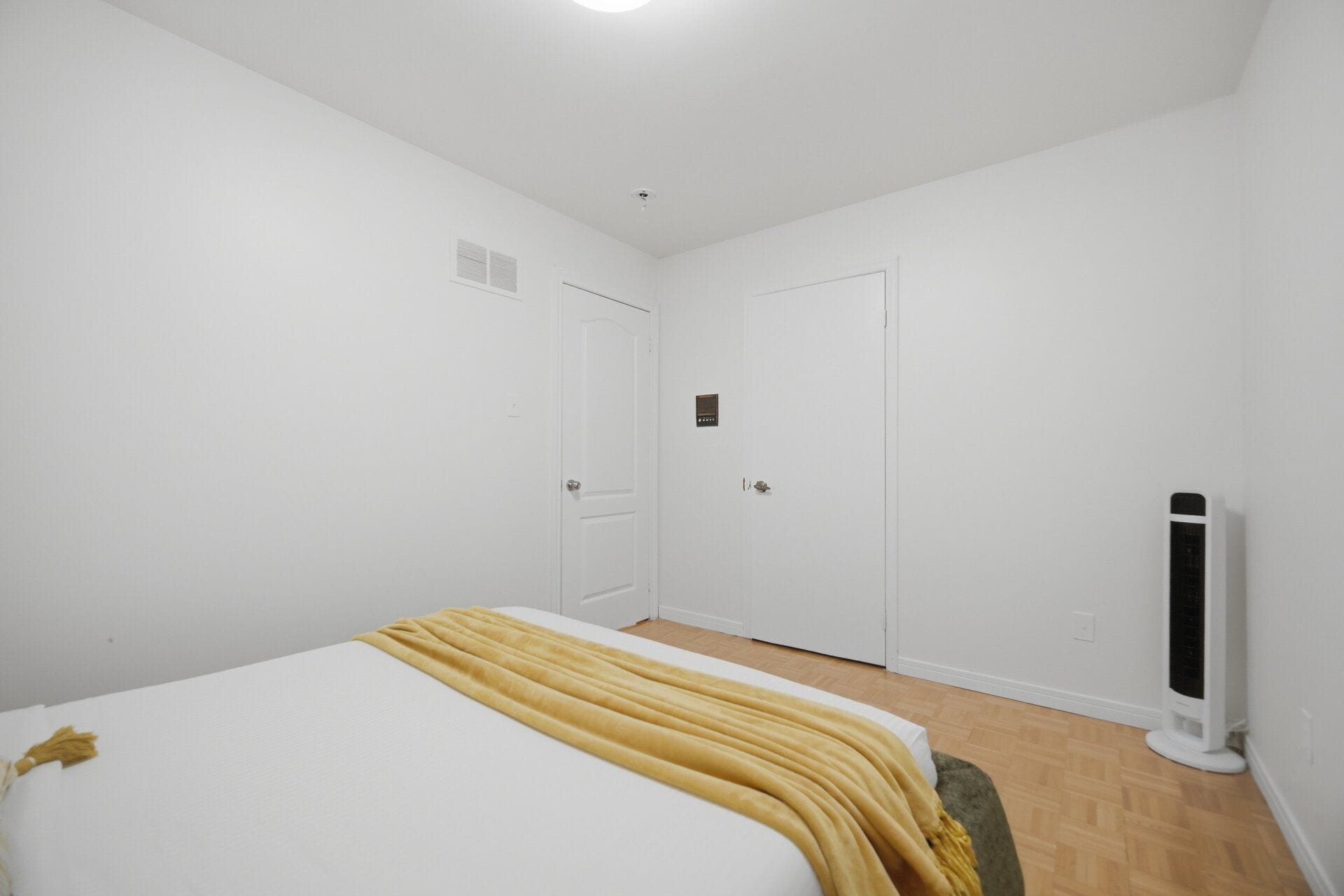 Un dormitorio con cama, dos puertas, un calentador y una pared blanca.
