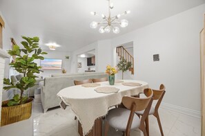 A dining area with a round table, chairs, and a chandelier.