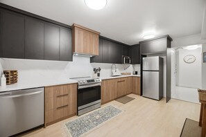 A modern kitchen with dark cabinetry, a stainless steel refrigerator, and a built-in oven.