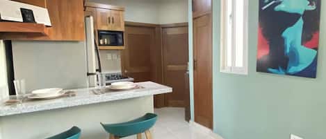 A kitchen with wooden cabinets, a microwave, and a countertop with stools.