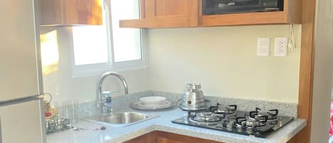 A kitchen with wooden cabinets, a microwave, a sink, and a gas stove.