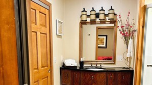 A bathroom with a wooden vanity, a large mirror, and a vase with flowers. - High end 4-bedroom countryside home in Shawano, WI. 2,800 sqft and spacious! (Shawano)