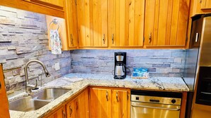 A kitchen with wooden cabinets, a stainless steel dishwasher, and a coffee maker. - High end 4-bedroom countryside home in Shawano, WI. 2,800 sqft and spacious! (Shawano)