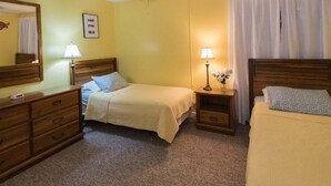 Ein Hotelzimmer mit zwei Betten, einem Deckenventilator, einer Nachttischlampe, einem Schminktisch und einem Spiegel.