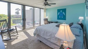 Ein Schlafzimmer mit Bett, Schreibtisch, Stuhl, Lampe und Blick ins Freie.