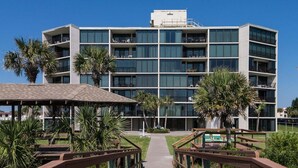 Ein mehrstöckiges Hotel mit Balkonen, einem überdachten Gang und Palmen.
