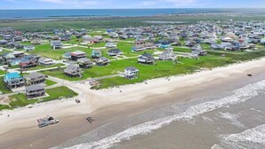 Vista aérea de una zona residencial costera con casas, una playa y un barco en el agua.