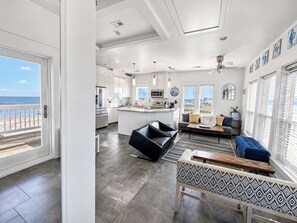 A modern interior with a kitchen, dining area, and living room, featuring a balcony with a view. - Beach FRONT | 180 degree VIEWS | REVIEWS!!! (Crystal Beach)