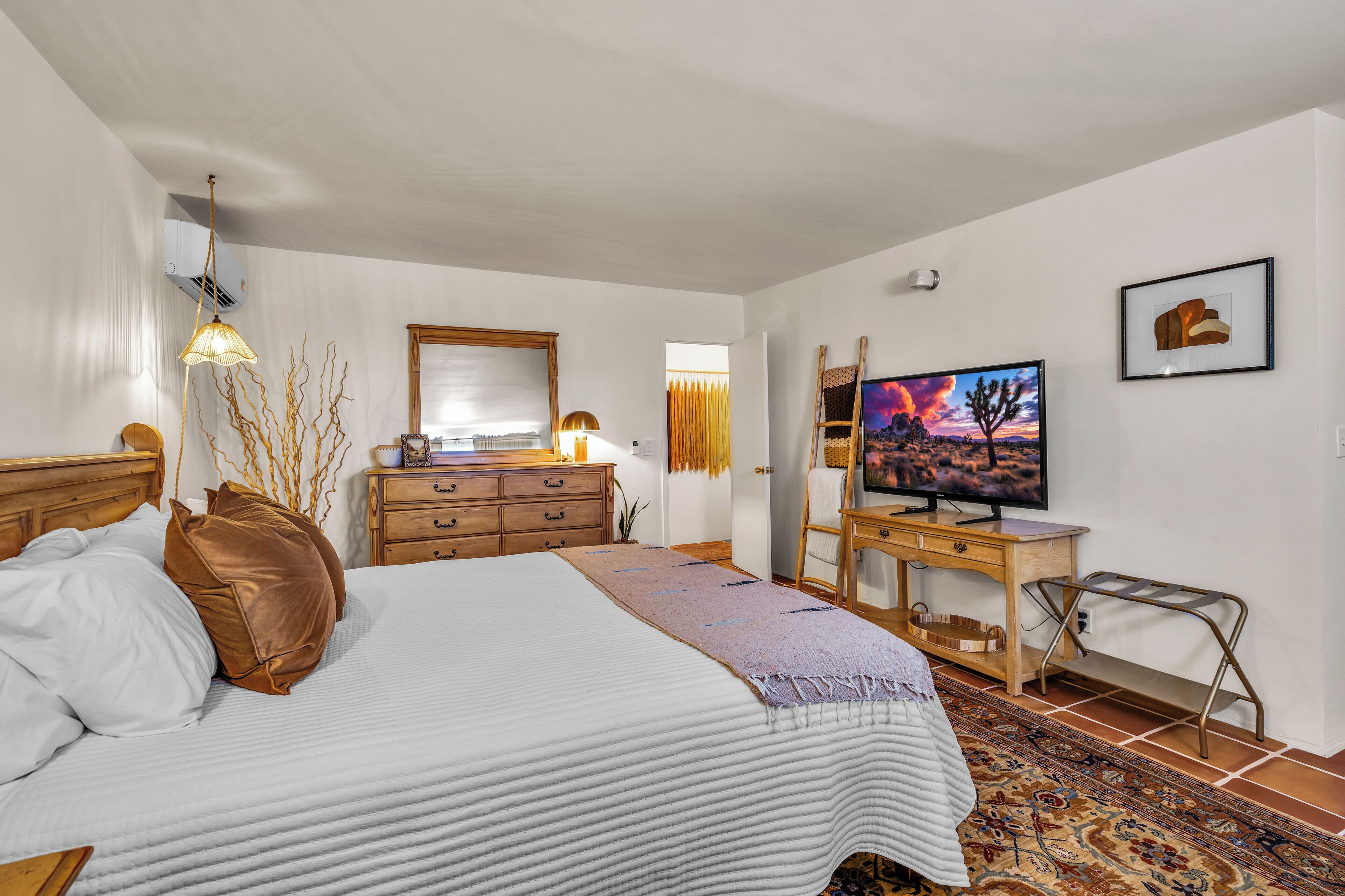 Une chambre à coucher comprenant un lit, une télévision, une commode, un bureau et une chaise.
