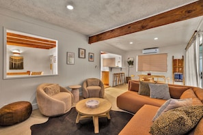 A modern living room with a sofa, armchairs, a coffee table, and a dining area with a table and chairs. - Boulder Oasis - 3 Bed 2 Bath Home in Yucca Valley (Yucca Valley)
