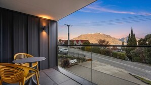 Un balcón con mesa y sillas, con vistas a una calle y montañas.