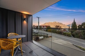 Ein Balkon mit Tisch und Stühlen mit Blick auf eine Straße und Berge.