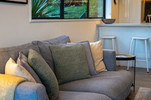 A grey sofa with multiple cushions in various textures and colors. - Queenstown Quarters - Residence I (Queenstown)