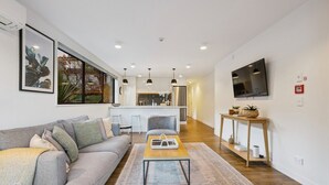 Una sala de estar moderna con un sofá, una mesa de centro y un televisor montado en la pared.