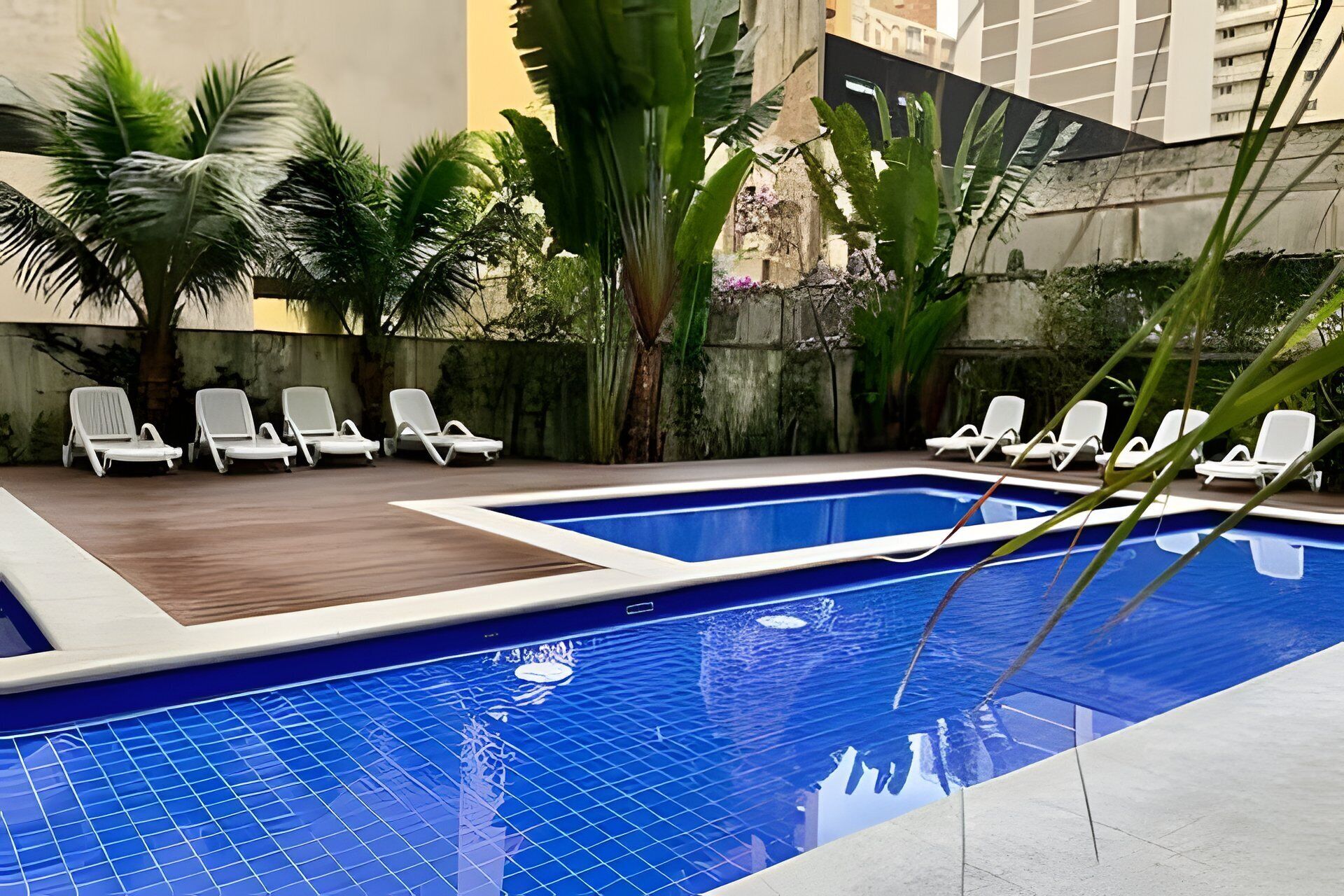 A swimming pool with white lounge chairs and tropical plants.
