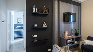 Una sala de estar moderna con televisor, sofá a rayas y una estantería con objetos decorativos.