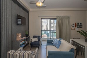 Un salon moderne avec un canapé, un fauteuil et un téléviseur fixé au mur.