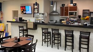 Una cocina moderna con una isla central, taburetes de bar y un comedor con mesa y sillas.