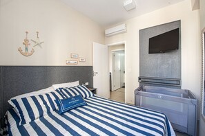 Habitación de hotel con una cama, un televisor, un aire acondicionado y una puerta que da a un baño.