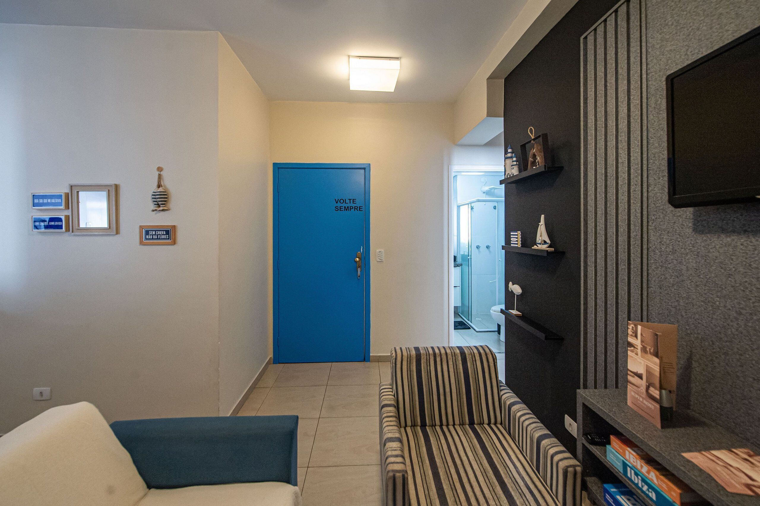 A hotel lobby with a blue door, striped sofa, and a flat-screen TV on the wall.