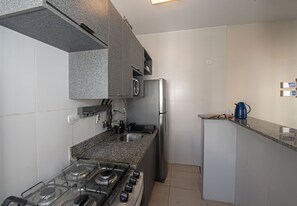 Una cocina moderna con estufa a gas, electrodomésticos de acero inoxidable y encimeras de granito.