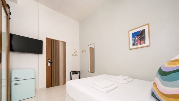 Quarto de hotel com cama, televisão, guarda-roupa e espelho.