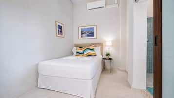 Quarto de hotel com cama, mesa de cabeceira com abajur e ar condicionado.