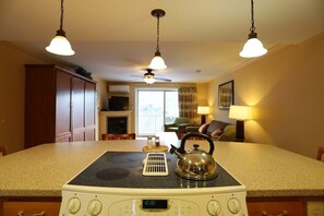 A kitchen with a stove, kettle, and a dining area with a table and chairs. - Leaf Peep at Pollard Brook! (Lincoln)