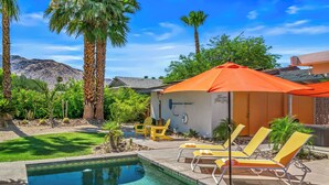 A swimming pool with lounge chairs and an umbrella, surrounded by palm trees and a mountain in the background. - 1962 TramView Palm Springs - Poolside Fun, Spa, Fire Pit & Views (Palm Springs)