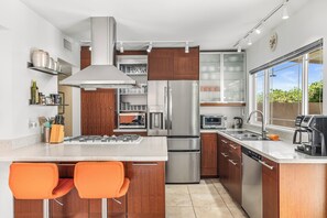 Een moderne keuken met roestvrijstalen apparatuur, houten kastjes en een groot raam met uitzicht.