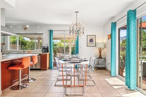 Una cucina moderna con zona pranzo, caratterizzata da un'isola centrale, sgabelli da bar e un lampadario.