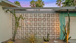 A cactus garden with a geometric fence, rocks, and a palm plant. - 1962 TramView Palm Springs - Poolside Fun, Spa, Fire Pit & Views (Palm Springs)