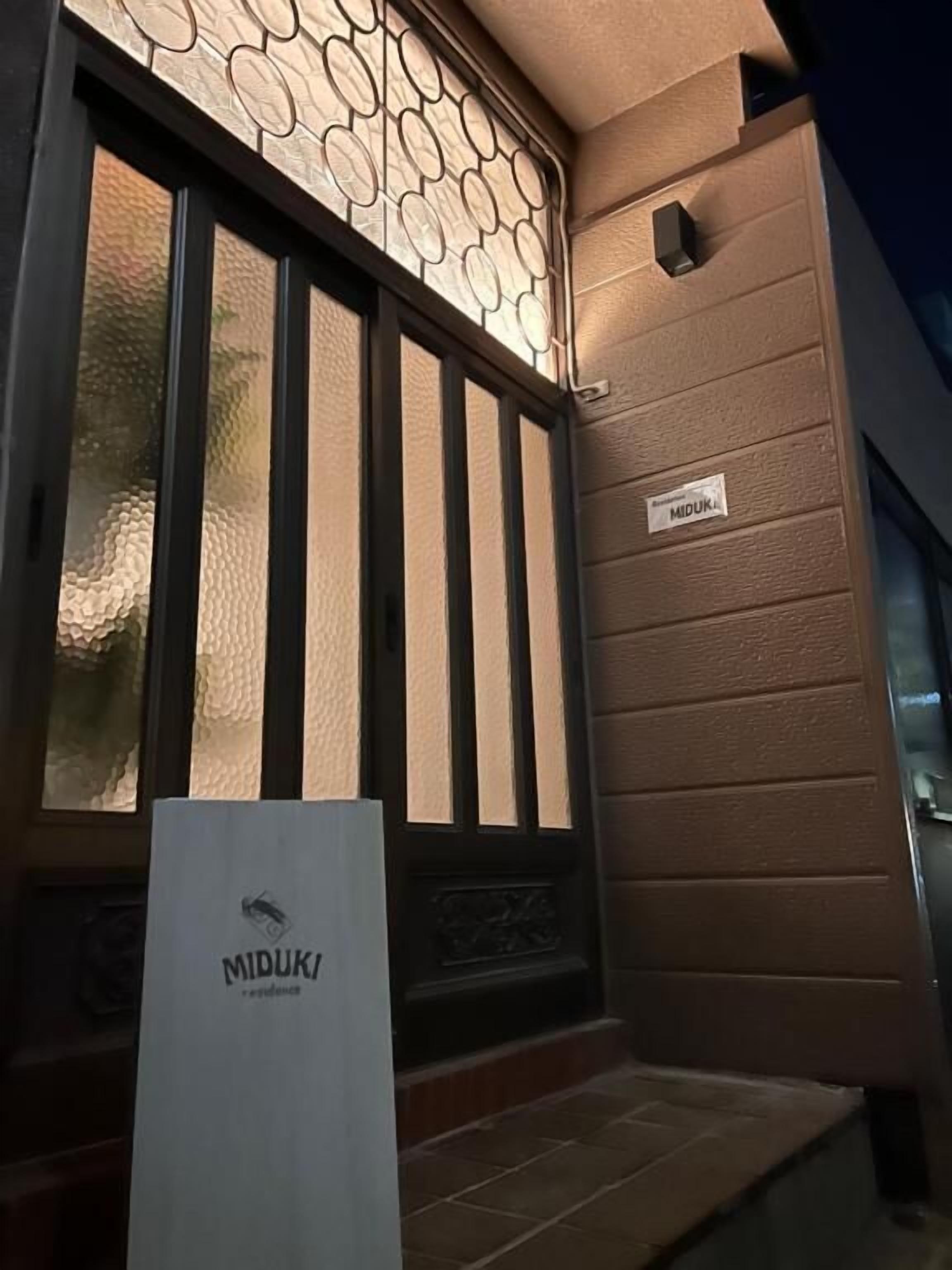 A door with a textured glass panel and a sign reading 'MIDUK.'